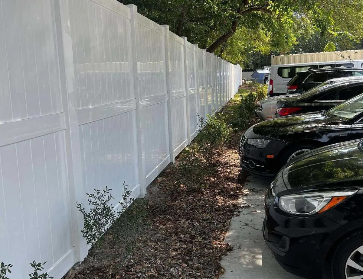 White vinyl commercial privacy fence installed along a parking area in Jacksonville, Florida.